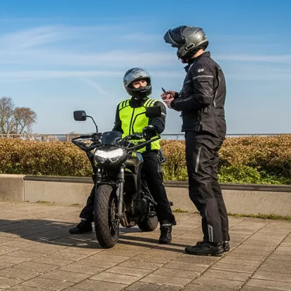 Instructeur geeft uitleg aan een leerling naast de lesmotor