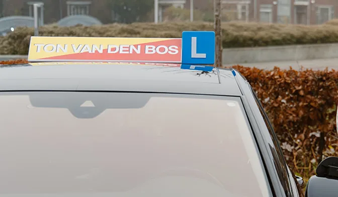 Daklicht met TON VAN DEN BOS en een L-bord op een lesauto