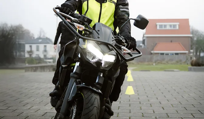 Motorrijder met hesje op de lesmotor