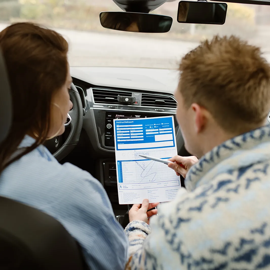 Leerling en instructeur bekijken samen een formulier in de lesauto