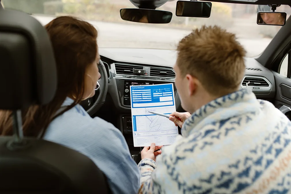 Een instructeur bespreekt de instructiekaart met een leerling in de lesauto